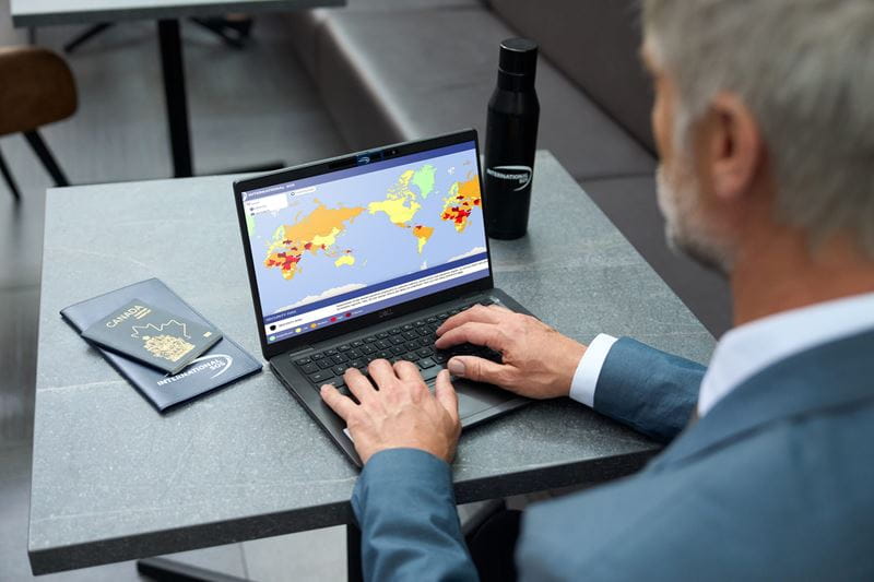 Mann am Laptop schaut auf eine Weltkarte
