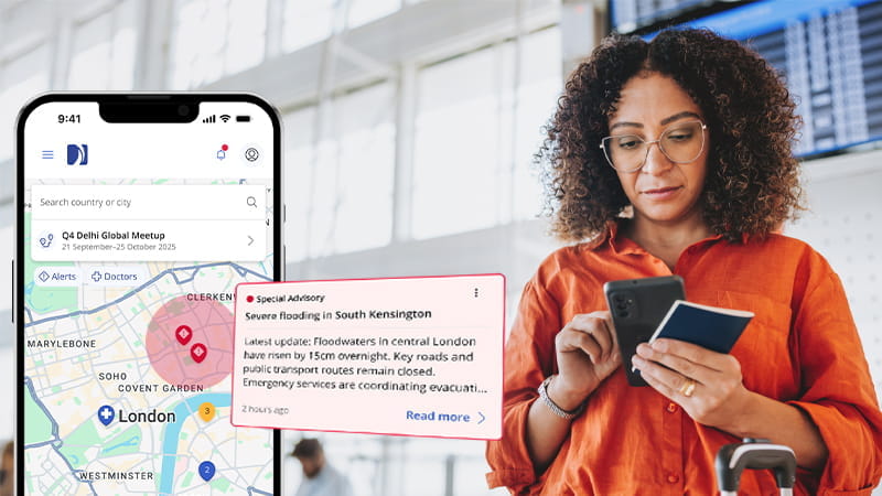 Eine Geschäftsreisende schaut auf eine Benachrichtigung der International SOS-App auf ihrem Handy.